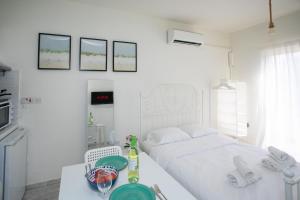 a white bedroom with a bed and a table with a plate at Palmove Makenzie Studio 4 in Larnaca