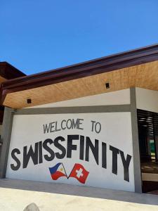 een teken dat zegt welkom op swissinity op een gebouw bij Swissfinity Beach Resort in Pangubatan