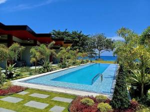 a swimming pool in front of a house at Swissfinity Beach Resort in Pangubatan