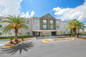a hotel with palm trees in front of a building at Comfort Inn & Suites Houma in Houma