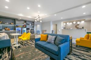 uma sala de estar com um sofá azul e cadeiras amarelas em Comfort Inn & Suites Houma em Houma