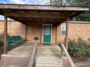 a wooden porch of a cabin with a green door at Cypress Landing Cabins 