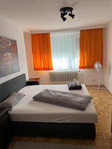 Schlafzimmer mit einem großen Bett und orangefarbenen Vorhängen in der Unterkunft City Appartement 4600 in Wels