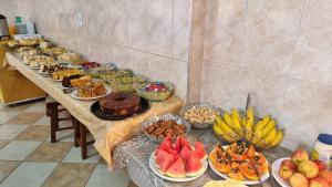 una mesa larga llena de diferentes tipos de alimentos en Hotel Pousada Recanto da Madá, en Aparecida