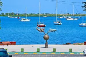 a statue of a woman and a fish on a ball in front of the water at NEW Comfy Stay with Pool Onsite Steps from Malecón in La Paz