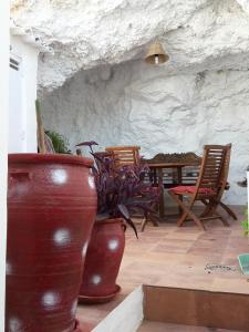 zwei große Vasen neben einem Tisch und Stühlen in der Unterkunft La Cueva Soleá in Algodonales