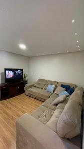 uma sala de estar com um sofá e uma televisão de ecrã plano em Apto climatizado 3 quartos a 3,7km da Vila Germânica em Blumenau