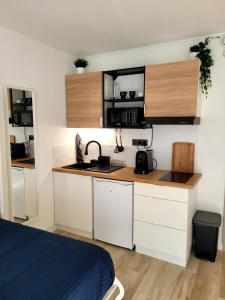 a small kitchen with white cabinets and a bed at Les Appartements De Lina By LG Immo - Self Check-In - in La Grande-Motte