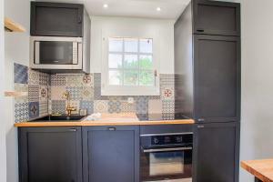 多維爾的住宿－Sweet Home - PiscineTennis - Deauville，厨房配有黑色橱柜、水槽和窗户。