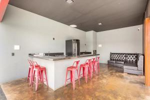 a kitchen with a bar with four red stools at Requinte, conforto e privacidade in Pirenópolis