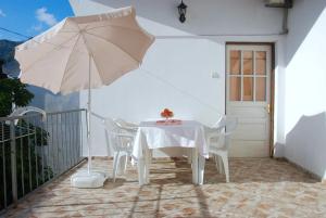 a white table and chairs with an umbrella on a balcony at Apartmani Bonik in Budva
