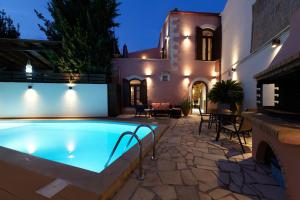 a swimming pool in front of a house at night at Stone Villa with swimming pool-BBQ! in Melidhónion