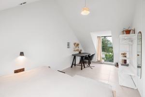 a white bedroom with a bed and a desk at The barn - Waasmunster in Waasmunster