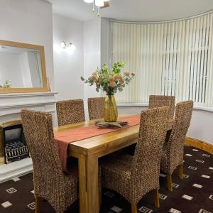 einen Esstisch mit Stühlen und eine Vase aus Blumen in der Unterkunft Large House/Contractors/Families in Birmingham