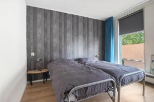 een slaapkamer met een bed met een grijze muur bij Appartement De Boppeslach in Marssum