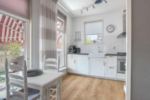 cocina con armarios blancos, mesa y ventana en Appartement De Boppeslach en Marssum
