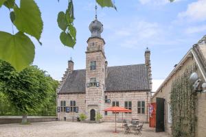 un antiguo edificio de piedra con una torre de reloj en Appartement De Boppeslach, en Marssum