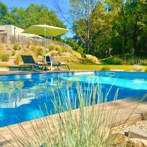 a swimming pool with two chairs and an umbrella at Chambres avec Jacuzzi privatif - Kassiopée Bed & Spa in Albi