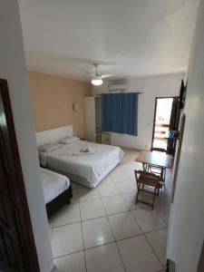a hotel room with two beds and a table at Pousada Cabufa in Cabo Frio