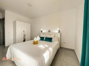 um quarto branco com uma grande cama branca com almofadas azuis em Fee4Me Gáldar, a pocos minutos del valle de Agaete em Gáldar