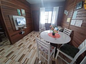 a dining room with a white table and chairs at Casa Barra do Sai in Itapoa