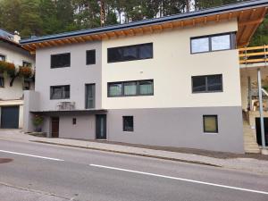 een wit gebouw met zwarte ramen op een straat bij Bergblick Wohnung Posch in Imst