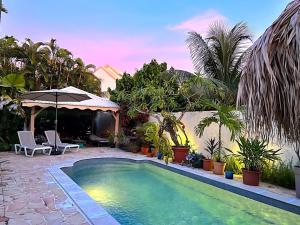 einen Pool in einem Garten mit Palmen in der Unterkunft Sweet Payot : Studio avec Spa privé et piscine in Le Lamentin