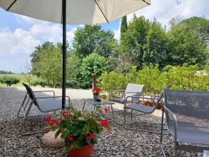 a patio with chairs and an umbrella and flowers at Cascina Cortese in Druento