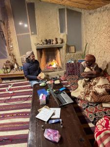 two men sitting in a room with a fireplace at Shamofs Farm in Siwa