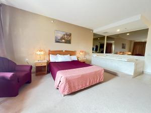 una camera con un grande letto e una vasca di Western Budget Motel Ponoka a Ponoka