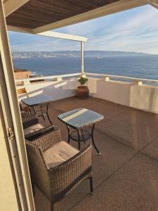 a balcony with two tables and chairs and the ocean at Apto. Reñaca 193 - Viña del Mar in Viña del Mar