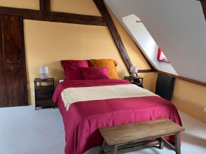 a bedroom with a bed with a red blanket and a bench at Gite LA FLEUR DE SEINE in Villequier