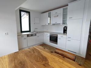 a kitchen with white cabinets and a wooden floor at Loft 29 in Ulm