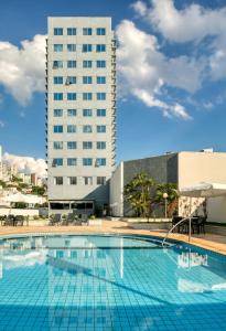 a large swimming pool with a tall building in the background at Mercure Belo Horizonte Savassi in Belo Horizonte