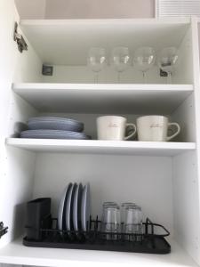 a white cabinet with plates and cups and dishes at Vytauto Septyni in Zarasai +4 photos