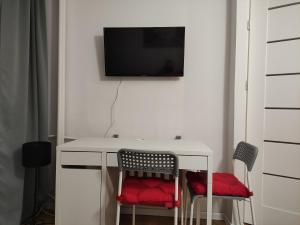 een wit bureau met 2 stoelen en een tv aan de muur bij Apartament Rondo ONZ in Warschau