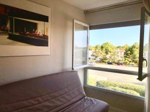 a living room with a couch and a large window at Studio - Pleine Mer - 1 avenue des Pays de Monts - 1-1 in Saint-Jean-de-Monts