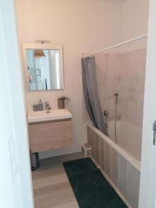 a bathroom with a sink and a tub and a mirror at LA MAISON BLEUE in Quiberon