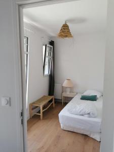 a white bedroom with a bed and a table at LA MAISON BLEUE in Quiberon