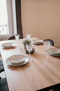 a wooden table with plates and glasses on it at Appartement d'Alexandre hyper centre-ville in Charleville-Mézières +14 photos