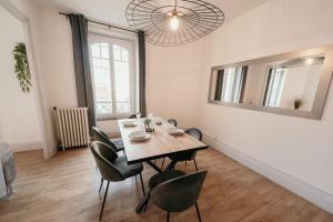 uma sala de jantar com uma mesa, cadeiras e um espelho em Appartement d'Alexandre hyper centre-ville em Charleville-Mézières