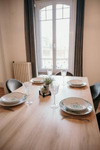 uma mesa de madeira com pratos e copos de vinho em Appartement d'Alexandre hyper centre-ville em Charleville-Mézières