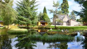 a house and a pond in front of a house at Reuben's Highland Retreat - Speyside in Carrbridge