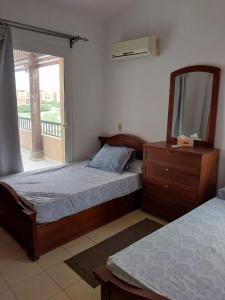 a bedroom with two beds and a dresser and a mirror at jenylyn`s chalet` families only` in Ain Sokhna
