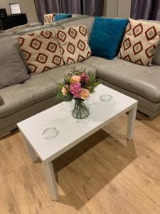 Una mesa de café blanca con un jarrón de flores. en Large Luxury appartment en Cobham