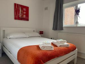 a bedroom with a bed with towels on a orange blanket at Elegant Serviced Apartment with Parking in Oxford in Oxford