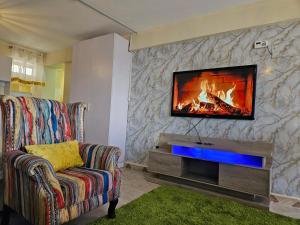 a living room with a tv on a stone wall at Airport Studio Apartments-JKIA in Nairobi