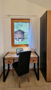 a desk with a laptop on it in front of a window at Chalet Michelangelo in Zermatt
