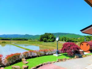 a garden with a clock in the middle of a pond at ゲストハウス　アンブレラ in Soma