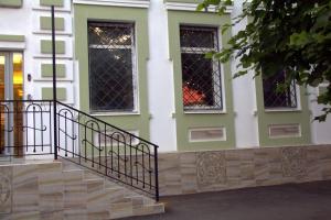 a green and white house with a staircase and windows at Hotel Kuban Vostok in Krasnodar